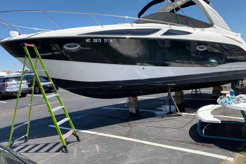 Slide: The Image of 2009 Bayliner 300 boat on stands in a parking lot with a green ladder nearby. - 10