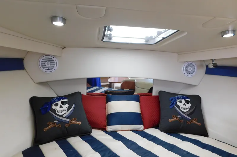 Slide: The Image of Interior of 2009 Bayliner 300 boat with pirate-themed pillows and striped bedding. - 55