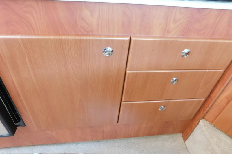 Slide: The Image of Wooden cabinetry in a 2009 Bayliner 300 boat interior, featuring drawers and a cabinet door. - 66