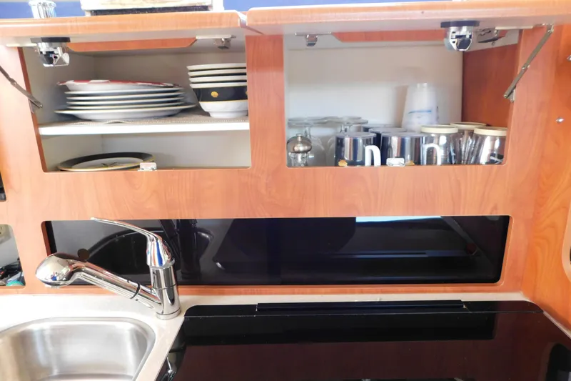 Slide: The Image of 2009 Bayliner 300 kitchen with wooden cabinets, dishes, and stainless steel sink. - 62
