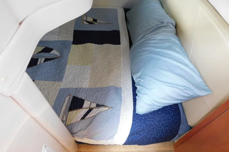 Slide: The Image of Cozy cabin bed in 2009 Bayliner 300 with nautical-themed quilt and blue pillow. - 82