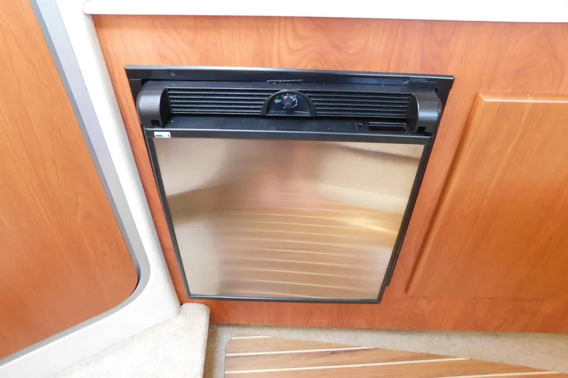 Slide: The Image of Compact refrigerator in 2009 Bayliner 300 boat interior, surrounded by wood paneling. - 76