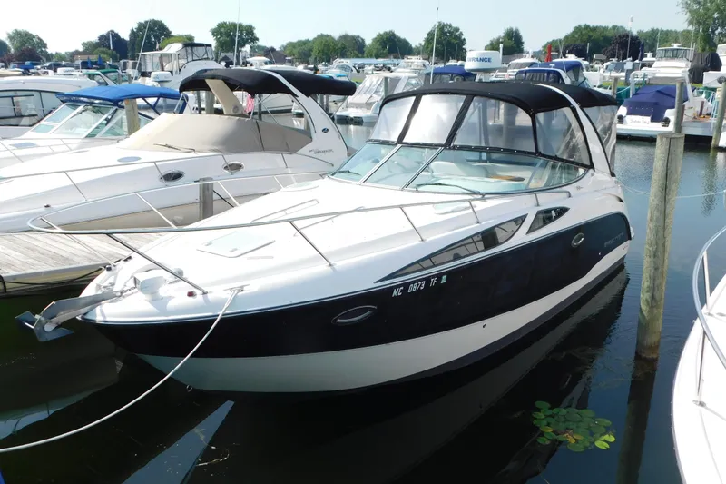 The Image of 2009 Bayliner 300 boat docked at a marina, featuring sleek design and black canopy. - 0