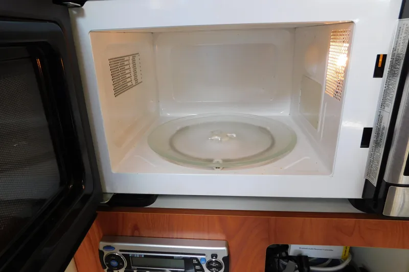 Slide: The Image of Open microwave inside a 2009 Bayliner 300 boat kitchen area. - 64