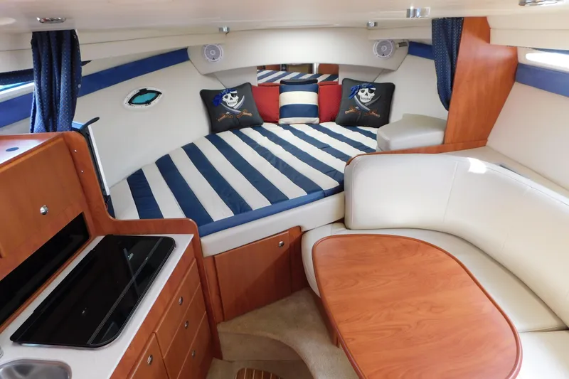 Slide: The Image of 2009 Bayliner 300 cabin interior with striped bedding, wooden cabinetry, and seating area. - 49
