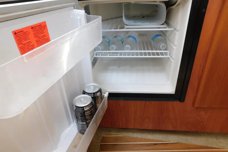 Slide: The Image of Mini fridge inside 2009 Bayliner 300 boat, stocked with water bottles and canned drinks. - 77