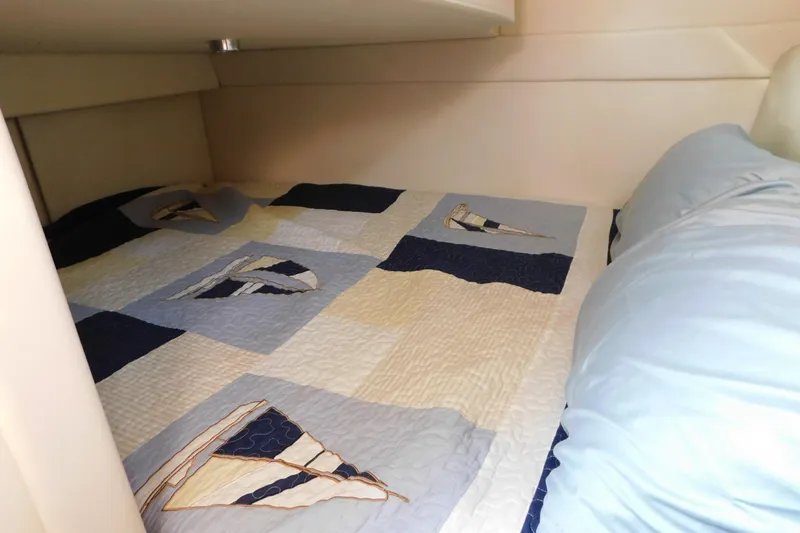 Slide: The Image of Cozy cabin bed in 2009 Bayliner 300 boat with nautical-themed quilt. - 84