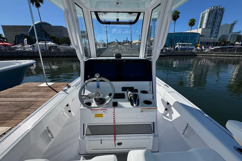 Slide: The Image of 2024 Sportsman Masters 247 Bay Boat cockpit with steering wheel and controls, docked by waterfront. - 7