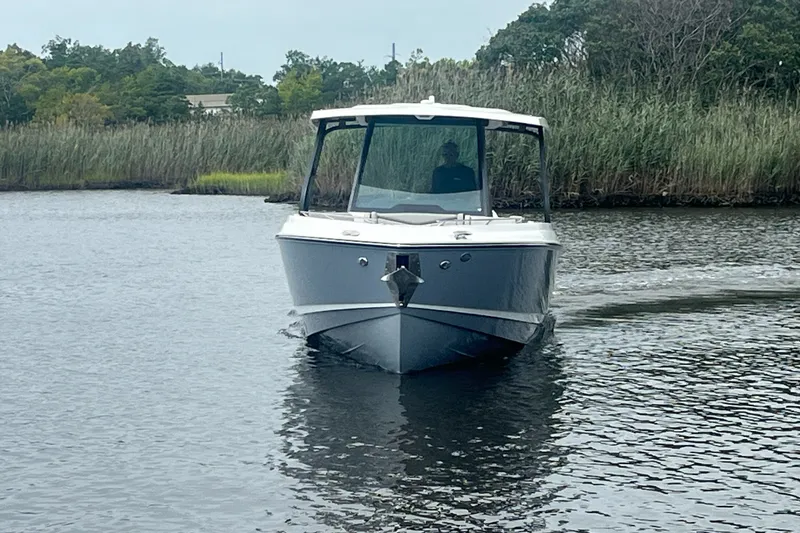 Slide: The Image of 2027 Monterey Elite 30 OB boat cruising on a calm river with lush greenery. - 5