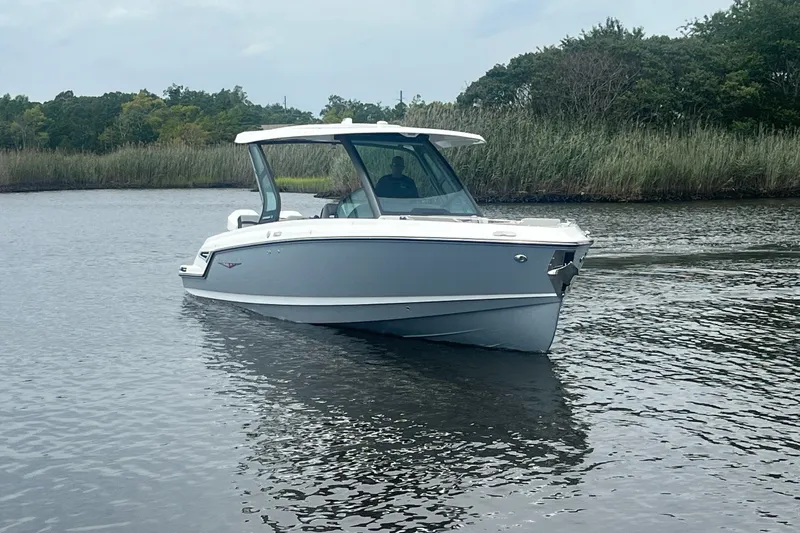 Slide: The Image of 2027 Monterey Elite 30 OB boat cruising on a calm lake with lush greenery. - 3