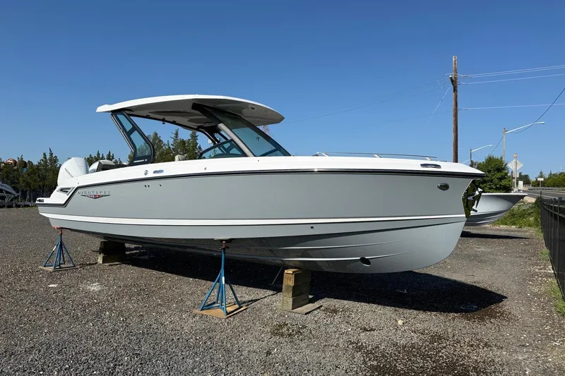 Slide: The Image of 2027 Monterey Elite 30 OB boat on stands, displayed outdoors under clear blue sky. - 1