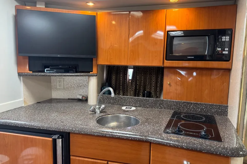 Slide: The Image of 2003 Formula 37 Performance Cruiser kitchen with TV, microwave, and stovetop. - 45