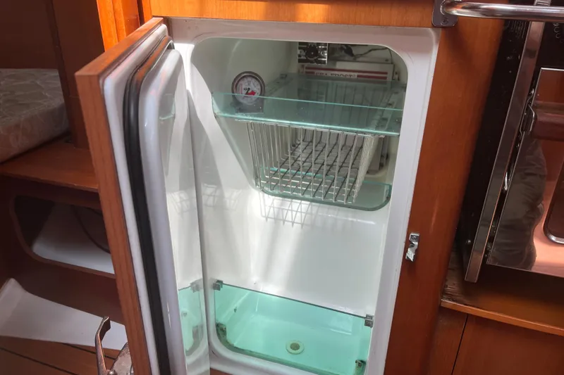 Slide: The Image of Open refrigerator inside 2006 Beneteau Oceanis Clipper 373 yacht, showcasing interior storage space. - 32