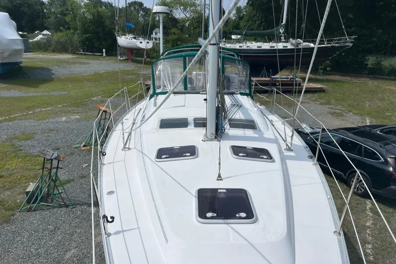 Slide: The Image of 2006 Beneteau Oceanis Clipper 373 sailboat on land, surrounded by greenery and parked cars. - 10