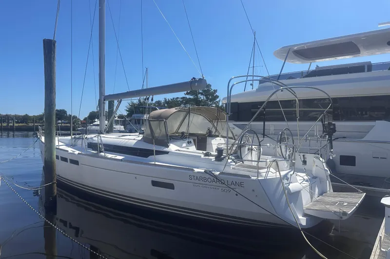 The Image of 2014 Jeanneau Sun Odyssey 509 sailboat docked at marina under clear blue sky. - 1