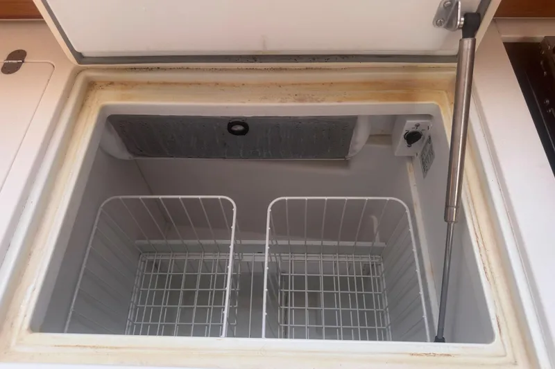 Slide: The Image of Open freezer compartment on 2014 Jeanneau Sun Odyssey 509 yacht, showing interior storage baskets. - 28