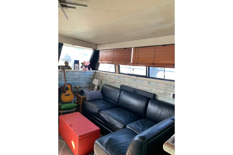Slide: The Image of Interior of 1989 Silverton 46 Aft Cabin with leather sofa, guitar, and red table. - 9