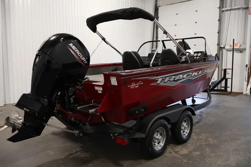 Slide: The Image of 2024 Tracker Targa V-18 Combo boat with Mercury engine in a garage setting. - 23