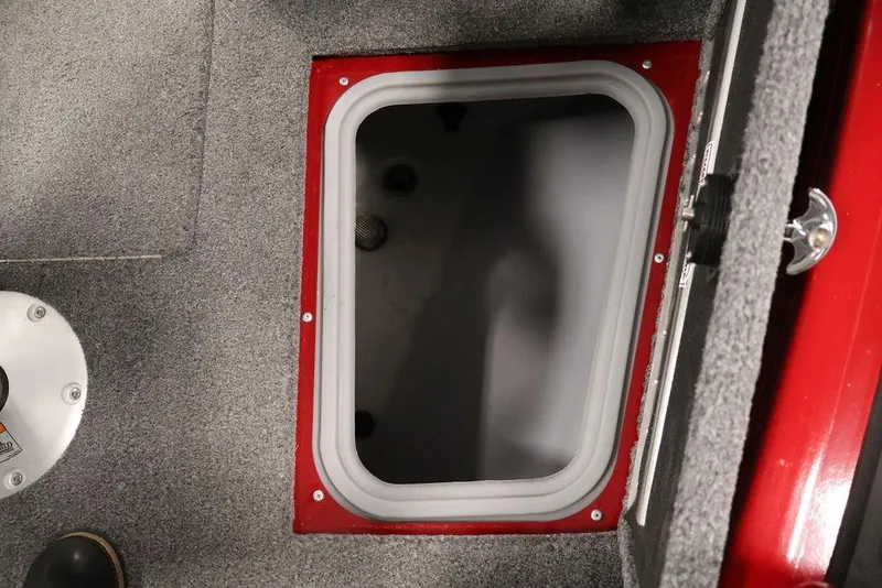 Slide: The Image of 2024 Tracker Targa V-18 Combo boat storage compartment with gray carpet and red trim. - 31