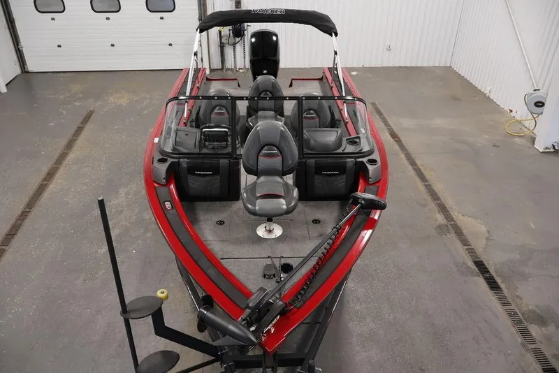 Slide: The Image of 2024 Tracker Targa V-18 Combo boat in a garage, featuring red and black seating. - 20