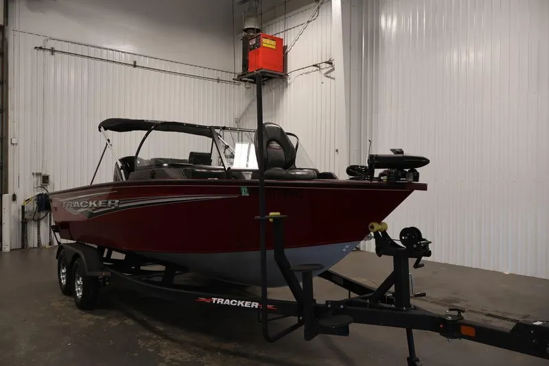 Slide: The Image of 2024 Tracker Targa V-18 Combo boat in a garage, red exterior, on a trailer. - 25