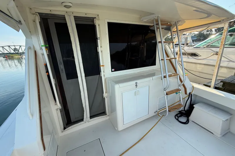 Slide: The Image of 1989 Viking 35 Convertible boat deck with ladder, storage, and marina view. - 13