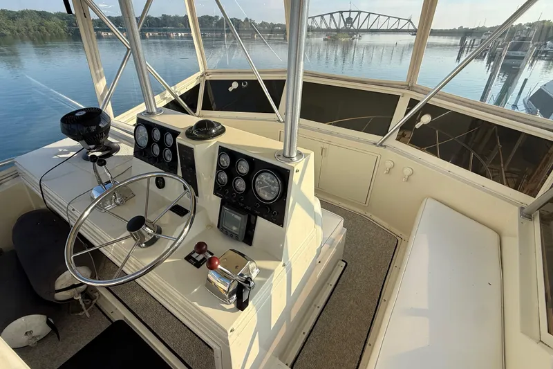 Slide: The Image of 1989 Viking 35 Convertible boat helm with steering wheel and gauges, overlooking serene waterway. - 17