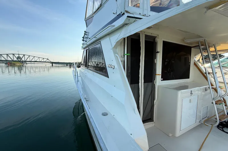Slide: The Image of 1989 Viking 35 Convertible yacht docked by a calm waterfront with bridge view. - 4