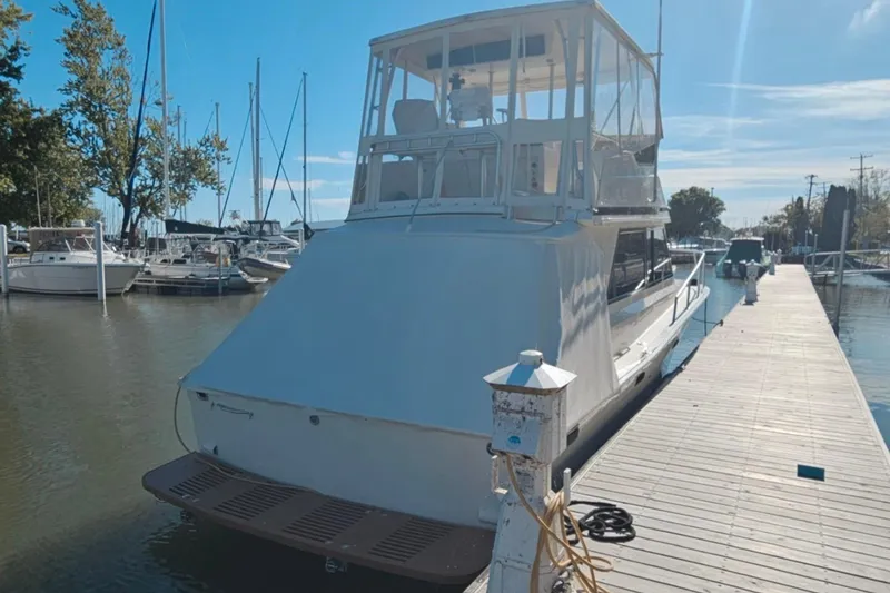 Slide: The Image of 1989 Viking 35 Convertible yacht docked at a marina under clear blue skies. - 2