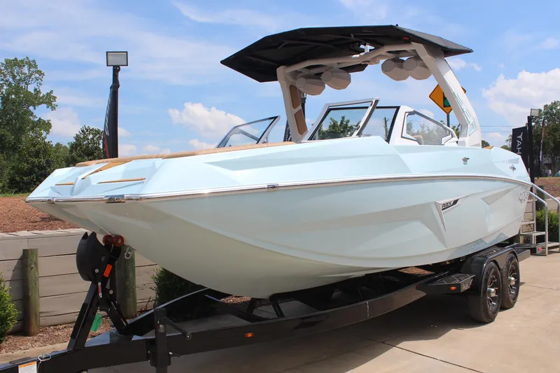 Slide: The Image of 2026 Tigé 24RZX boat on trailer, sleek design, light blue color, sunny day. - 2