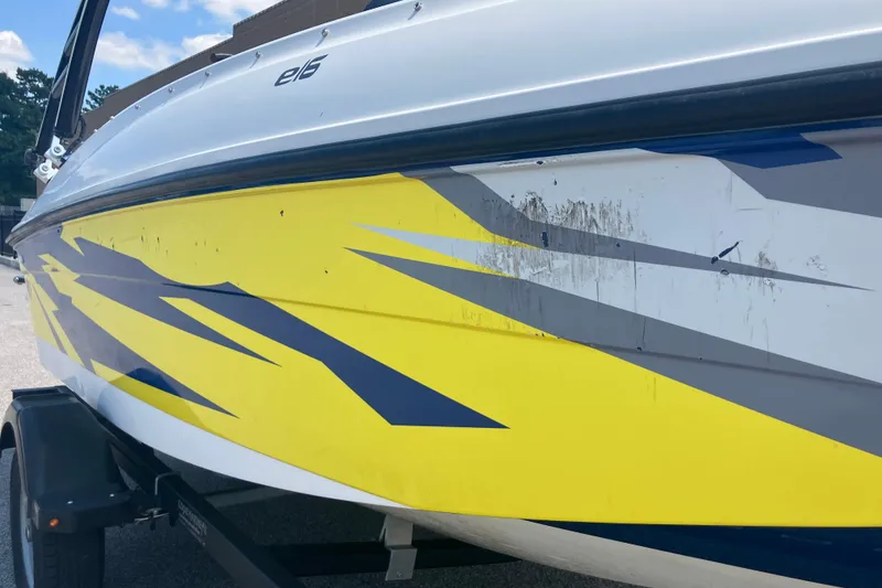 Slide: The Image of 2018 Bayliner Element E16 boat with yellow and blue graphics on trailer. - 2