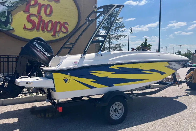 Slide: The Image of 2018 Bayliner Element E16 boat with vibrant yellow and blue design, parked outside Bass Pro Shops. - 1