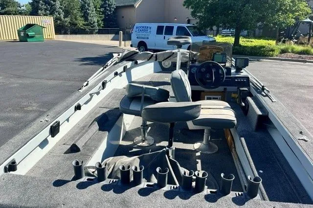 Slide: The Image of 1995 Bass Tracker Pro 17 boat with seating and fishing rod holders in a parking lot. - 2