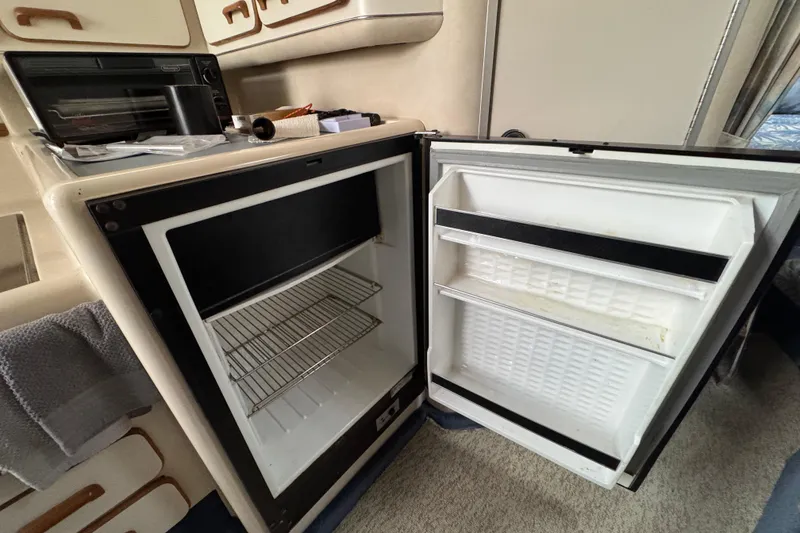 Slide: The Image of Open refrigerator inside 1993 Sea Ray Sundancer 330 boat cabin, showing interior shelves. - 19