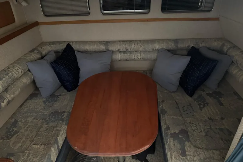 Slide: The Image of Interior of 1993 Sea Ray Sundancer 330 with cushioned seating and wooden table. - 13