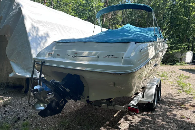 Slide: The Image of 1998 Sea Ray 260 Signature boat on trailer, covered with blue tarp, parked outdoors. - 4