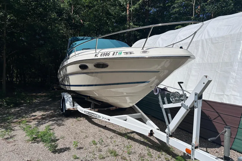 Slide: The Image of 1998 Sea Ray 260 Signature boat on trailer, parked outdoors near trees. - 2