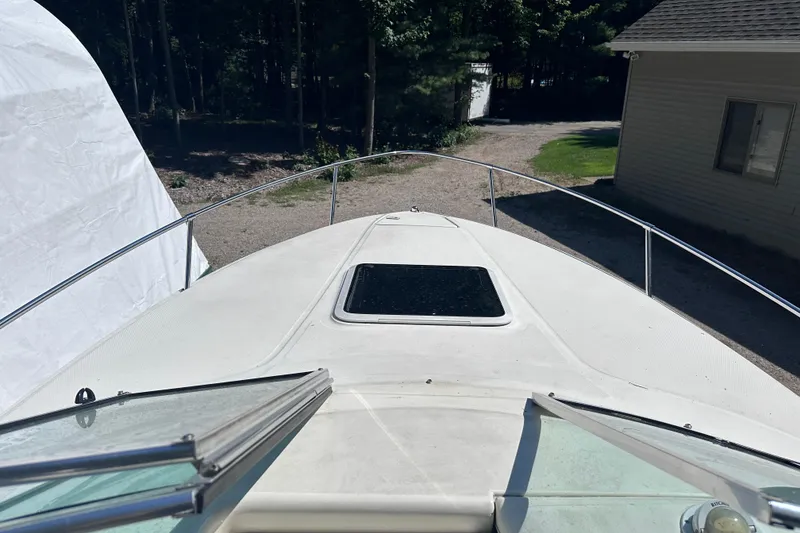Slide: The Image of 1998 Sea Ray 260 Signature boat deck with open hatch, surrounded by trees and buildings. - 9