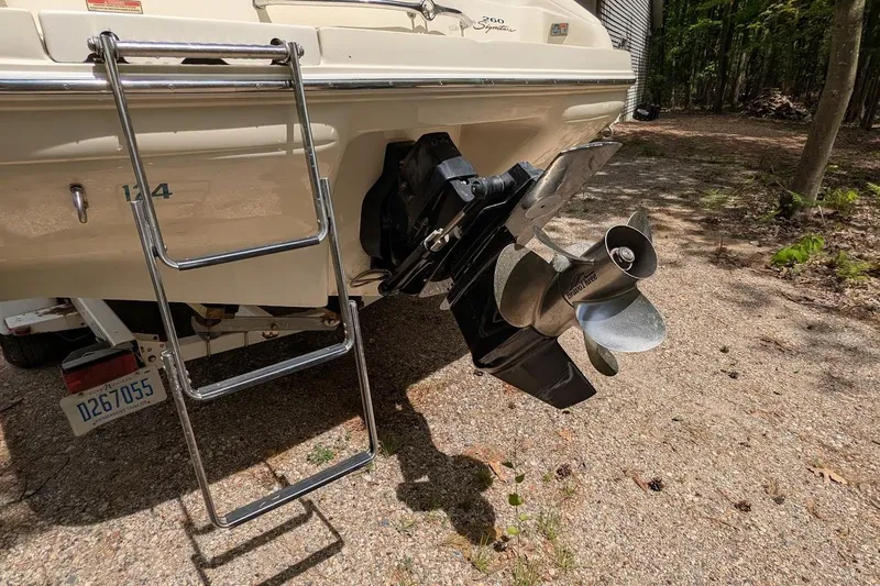 Slide: The Image of 1998 Sea Ray 260 Signature boat stern with ladder and propeller, parked on gravel. - 22