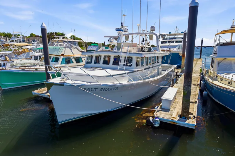 Slide: The Image of Boat docked at marina, Dixon 55 model, 2018, named "Salt Shaker," surrounded by other vessels. - 9