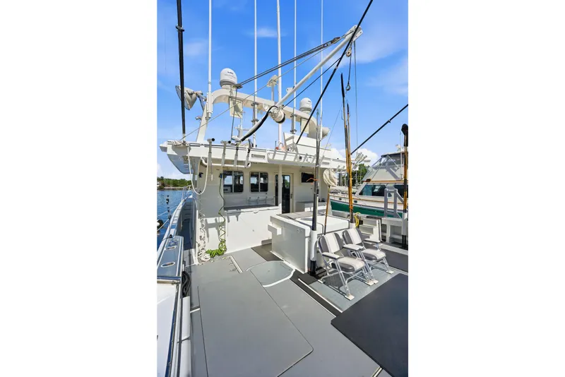 Slide: The Image of Dixon 55 boat deck, 2018 model, featuring fishing rods and seating under a clear blue sky. - 29