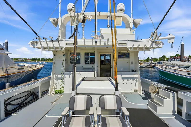 Slide: The Image of Fishing deck of 2018 Dixon 55 boat, equipped with rods and seating, docked at marina. - 55