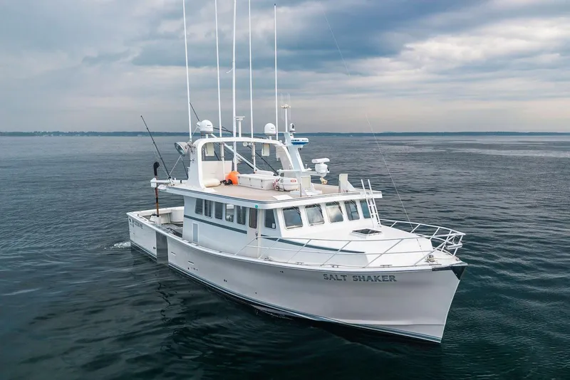 The Image of A 2018 Dixon 55 boat named "Salt Shaker" cruising on calm waters under a cloudy sky. - 1
