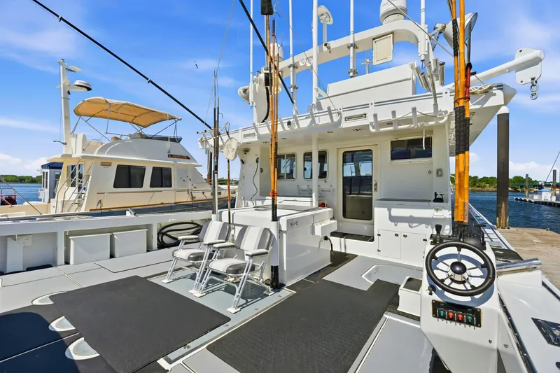Slide: The Image of Luxury Dixon 55 yacht deck, 2018 model, featuring seating and fishing equipment at marina. - 24