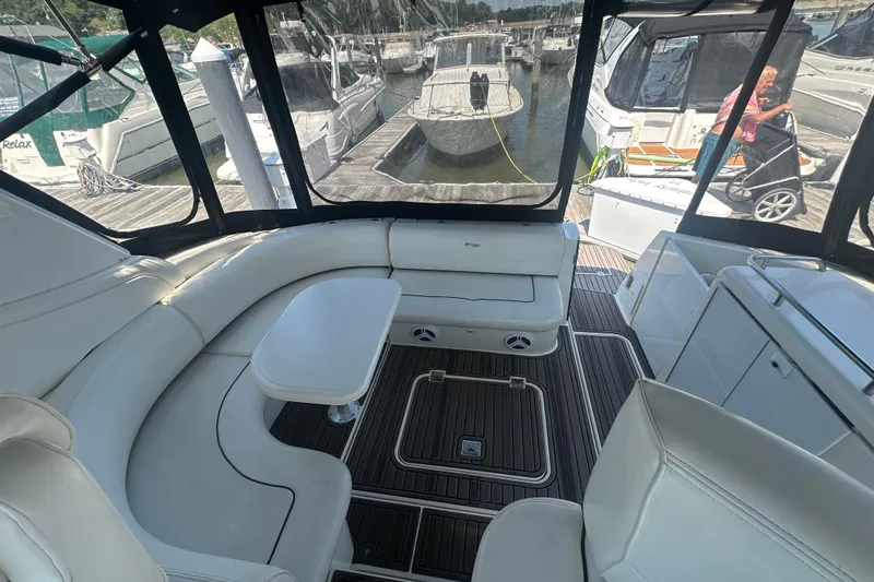 Slide: The Image of Interior of 2006 Cruisers Yachts 370 Express with white seating and table, docked at marina. - 12