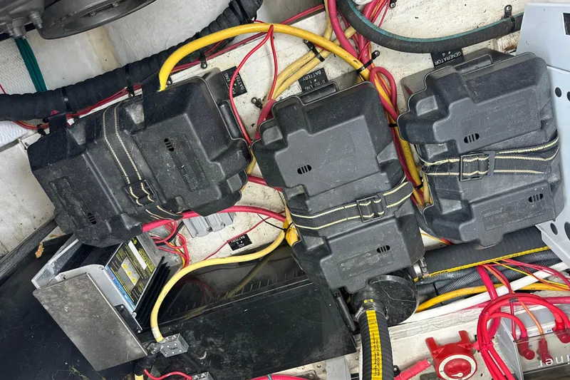 Slide: The Image of Three black battery boxes with yellow and red cables in a boat's engine compartment. - 44