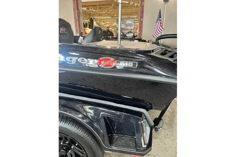 Slide: The Image of 2026 Ranger Z518 Cup-Equipped boat, black finish, displayed indoors with American flag. - 11