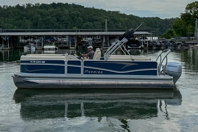 Slide: The Image of 2020 Premier 230 Sunsation pontoon boat on a calm lake near a marina. - 18