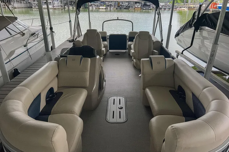 Slide: The Image of 2020 Premier 230 Sunsation pontoon boat interior with plush seating at marina. - 32