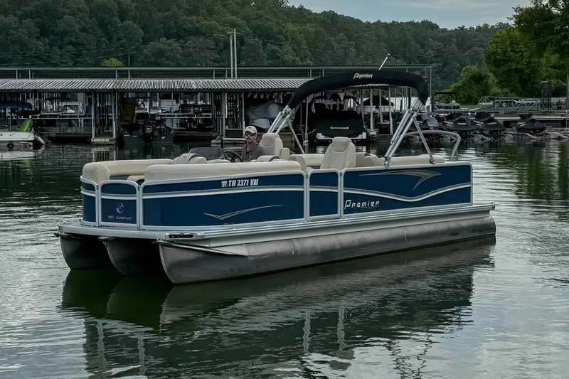 Slide: The Image of 2020 Premier 230 Sunsation pontoon boat on a calm lake near a marina. - 17